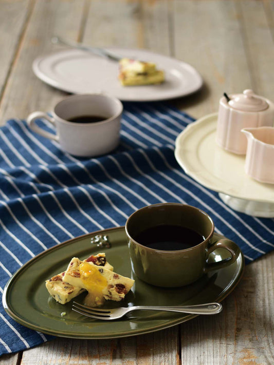 Studio M' Malta Oval Plate 28cm in an earthy green glaze, in an afternoon tea table seeting.