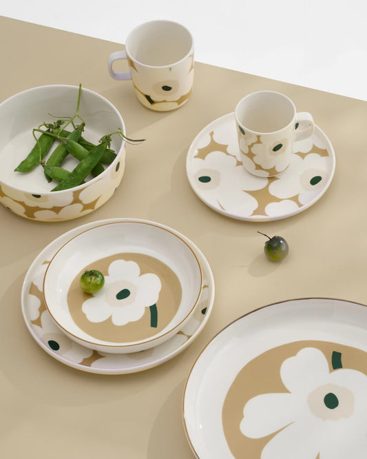 A lifestyle shot of the Marimekko Oiva collection featuring the iconic Unikko poppy print in dark green, beige, and light sand.