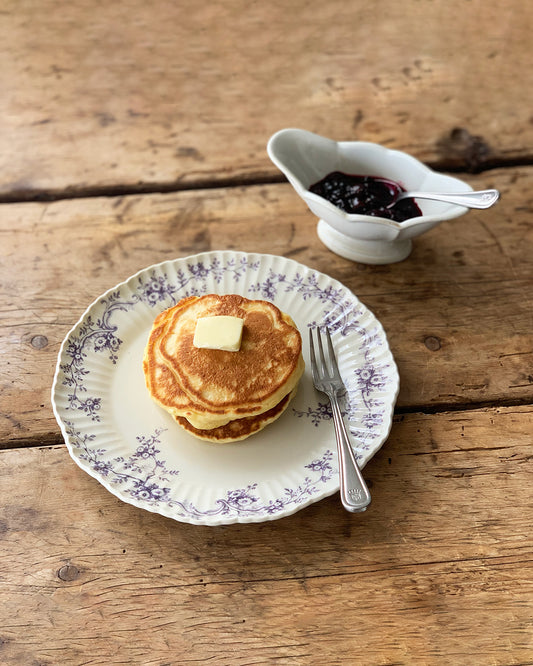 Studio M' Audrey 200 Plate in lavender porcelain, featuring a scalloped lace-like rim and an English garden-inspired floral relief pattern. Used to serve pancakes.
