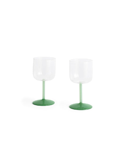 Side-angle view of a set of two HAY Tint Wine Glasses, showcasing minimalist clear borosilicate glass bowls resting on delicate stems in jade light green and jade dark green.