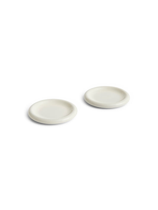 Side angle of two HAY Barro terracotta 18cm plates showcasing a clean high-gloss off-white glaze and distinctive natural rolled edges.