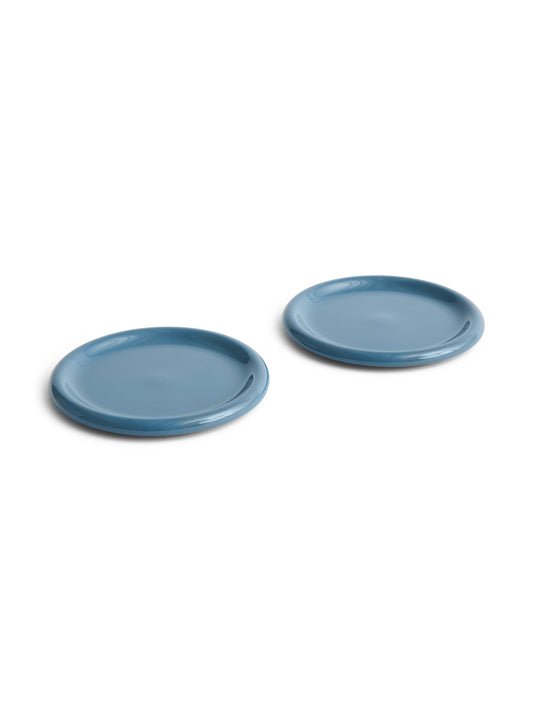 Side angle of two large 24cm HAY Barro terracotta dinner plates showcasing a rich high-gloss dark blue glaze and distinctive natural rolled edges.