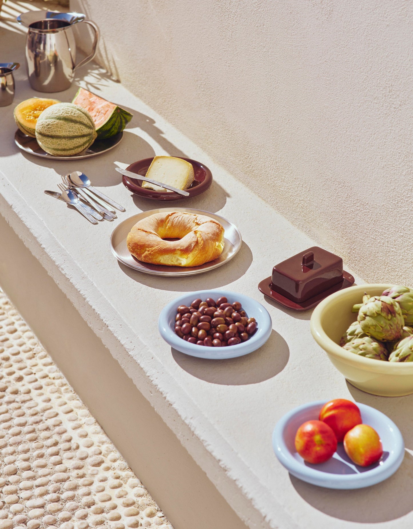 Close-up veiw of the outdoor setting of Hay light blue Barro bowls, paired with other Hay tableware products.