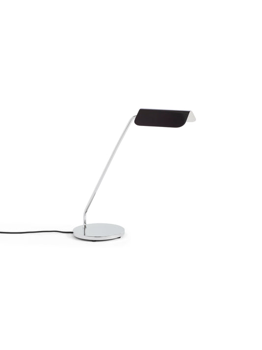 Side-angle view of the HAY Apex Desk Lamp featuring a folded steel shade in matte iron black, powerfully contrasted against a sleek, chrome-plated angled base.