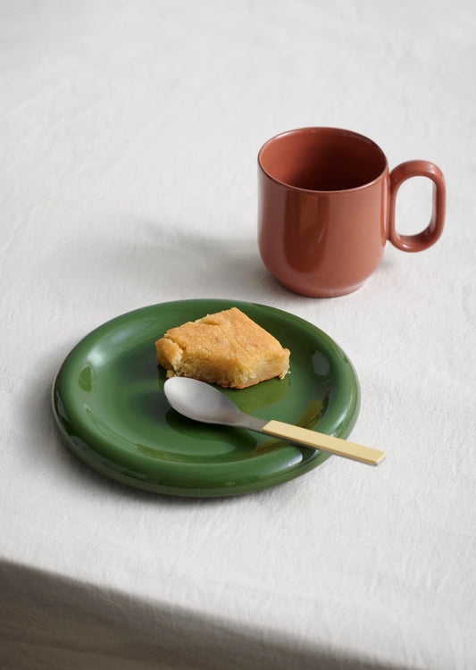 Hay Barro Plate 18cm in Green paired with an orange mug at breakfast.