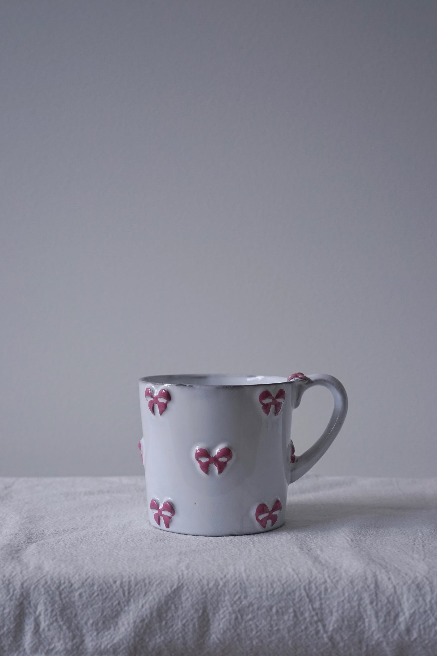 CARRON Paris handmade white ceramic Nœud-Nœud Trianon mug in medium, featuring a hand-painted dusty rose bow detail.
