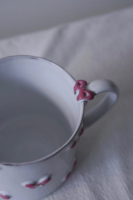 Close up of Carron Paris Noeud Noeud Mug in dusty rose, with a small pink bow decoration on the handle and matching pink bow details around the body.