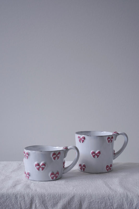 CARRON Paris handmade white ceramic Nœud-Nœud Trianon mug featuring a hand-painted dusty rose bow detail, available in small and medium.
