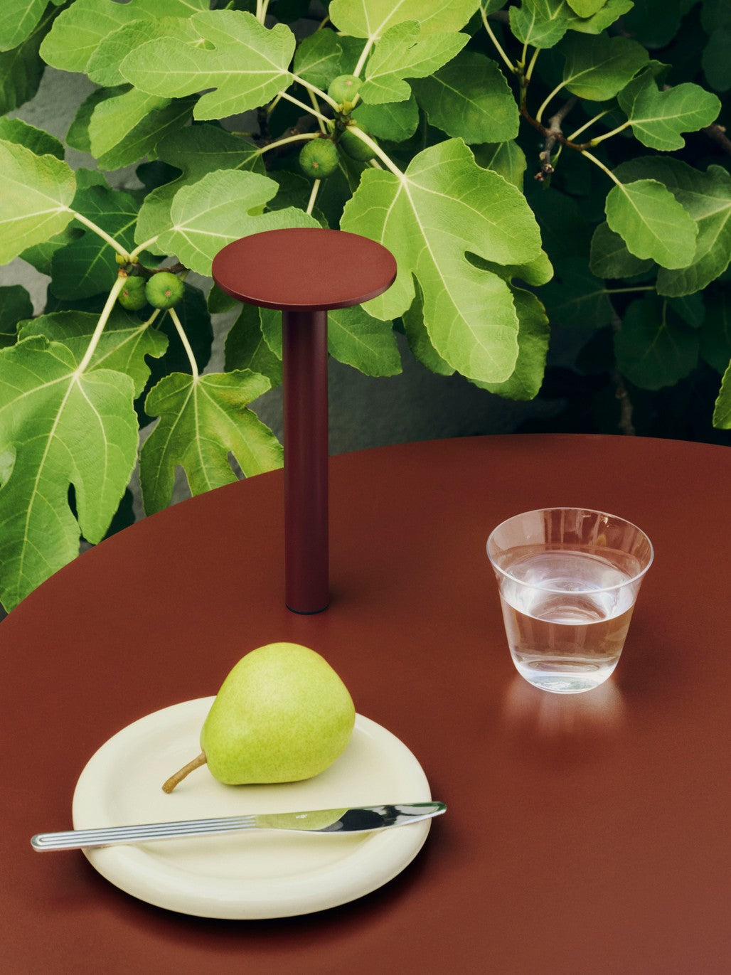 Hay barro plate 18cm in off-white on a red side table with a water glass.