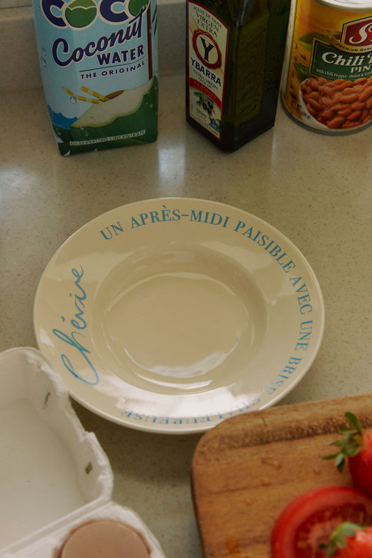 Hotel Paris Chill Lazy Vibe Side Plate light blue next to a cutting board and cooking ingredients.