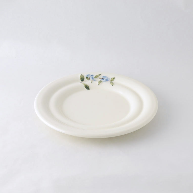A pack shot of Studio M' Myrtille Dessert Plate in warm cream ceramic, from a side angle.