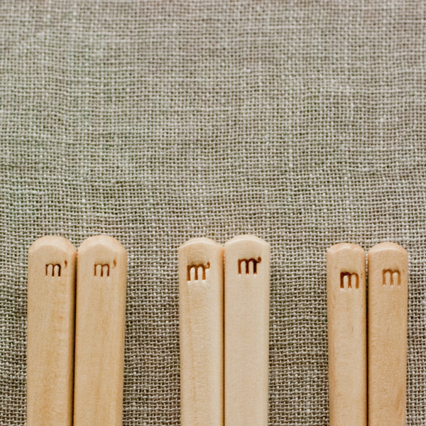 A close up shot of Studio M' Gros Maple Chopsticks 22.5cm featuring Studio M' logo at the end of the chopsticks. 