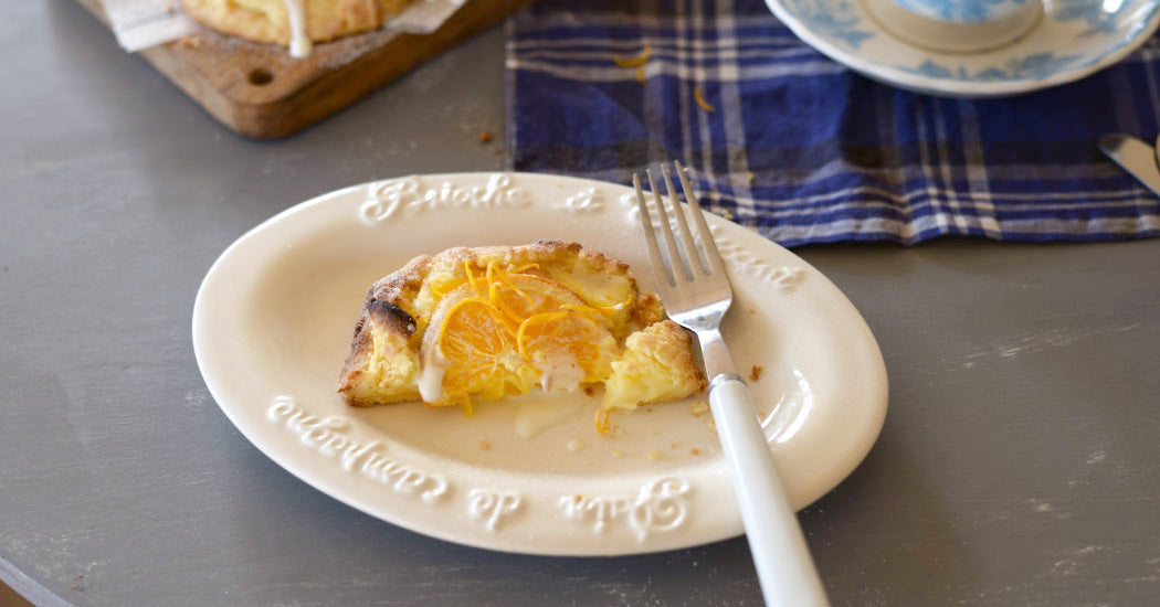Studio M Creamware Plate L served with fresh fruit tart and a white dessert fork on a grey bench.