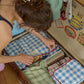 A woman packing clothes into a vintage brown suitcase on a wooden floor. The suitcase is filled with Hotel827 cotton travel pouches. 