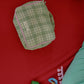 Hotel827 small travel pouch in evergreen lies on a red blanket.
