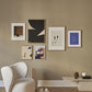 An art wall including The Togo by Hanna Peterson and other art prints in a modern interior with a white armchair in a living room setting.