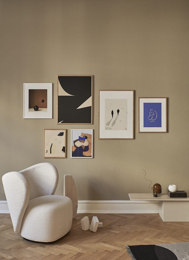 An art wall including The Togo by Hanna Peterson and other art prints in a modern interior with a white armchair in a living room setting.