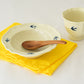 Studio M' Early Bird 170 porcelain bowl featuring a hand-painted blue swallow relief on a scalloped floral rim, paired with Early Bird Mug on a white dinning table. 