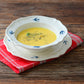 Studio M' Early Bird 170 porcelain bowl featuring a hand-painted blue swallow relief on a scalloped floral rim. Used as a soup bowl in the photo, paired with an Early Bird Plate. 