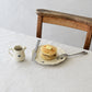 Studio M Early Bird small creamer next to a plate of pancakes on a white table cloth.