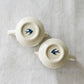 A close up shot of the base of two Studio M Early Bird small creamers.