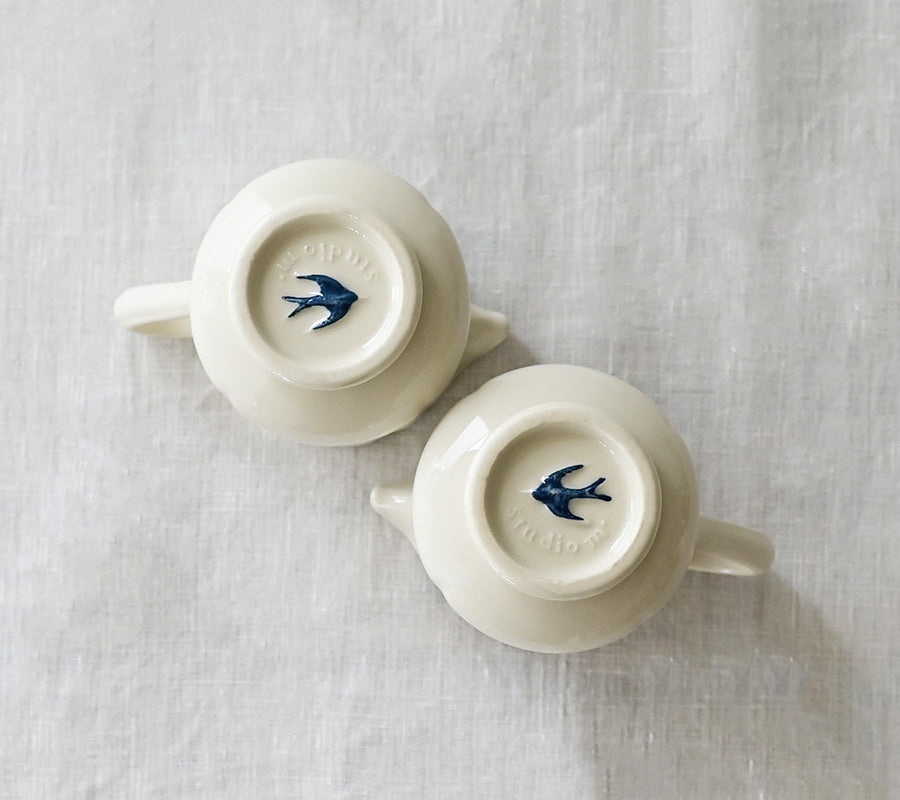 A close up shot of the base of two Studio M Early Bird small creamers.