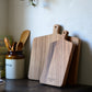 Studio M Japanese solid walnut cutting board collection in square and oblong, standing on a wooden kitchen bench. 