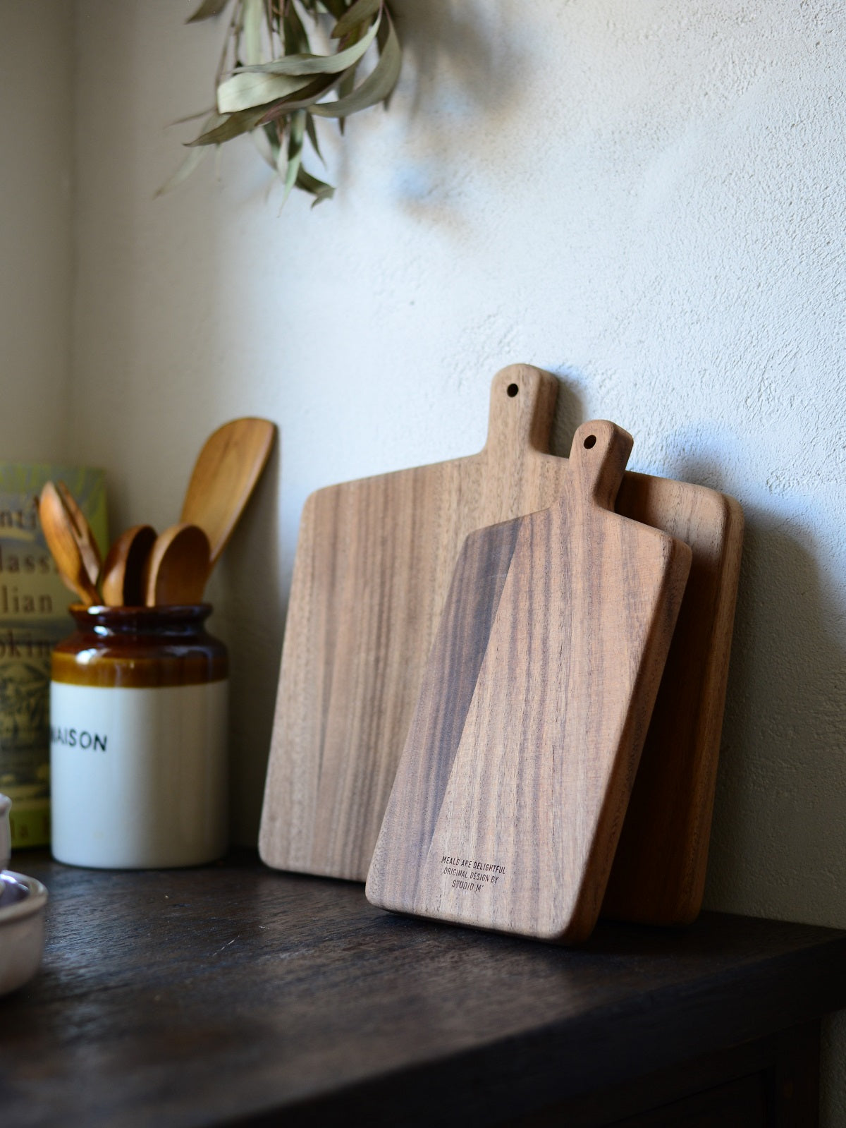 Studio M Japanese solid walnut cutting board collection in square and oblong, standing on a wooden kitchen bench. 