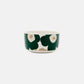 Side-angle view of the Marimekko Oiva 500ml white stoneware bowl featuring the iconic Unikko poppy print in dark green, beige, and light sand.
