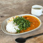 Studio M Karil 25cm oval earthenware plates in ecru colour serving curry and rice on a wooden table.