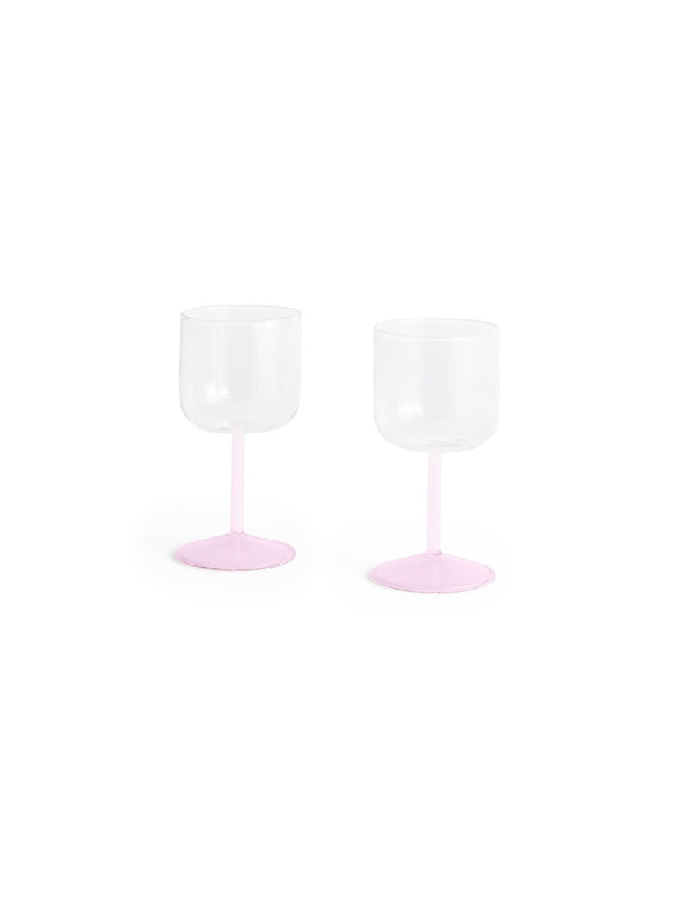 Side-angle view of a set of two HAY Tint Wine Glasses, showcasing minimalist clear borosilicate glass bowls resting on delicate stems in jade light pink and light pink.