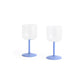 Side-angle view of a set of two HAY Tint Wine Glasses, showcasing their minimalist clear borosilicate glass bowls resting on delicate jade light blue stems.