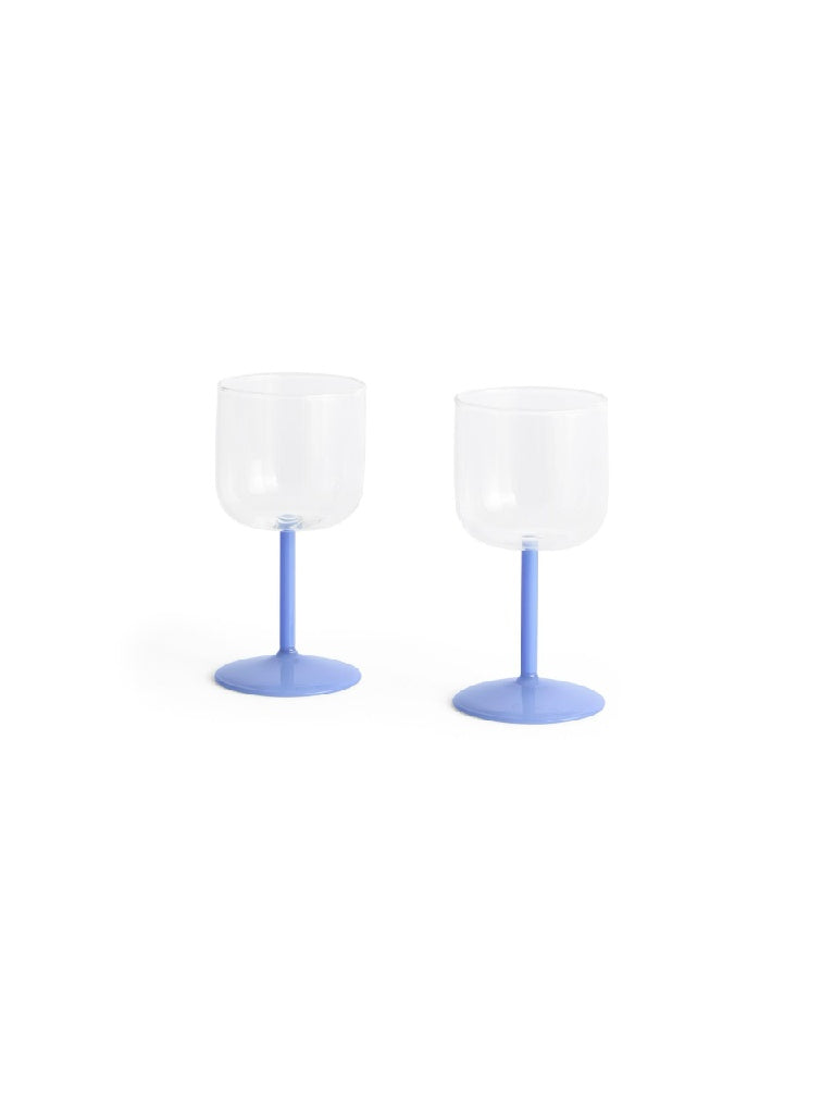Side-angle view of a set of two HAY Tint Wine Glasses, showcasing their minimalist clear borosilicate glass bowls resting on delicate jade light blue stems.