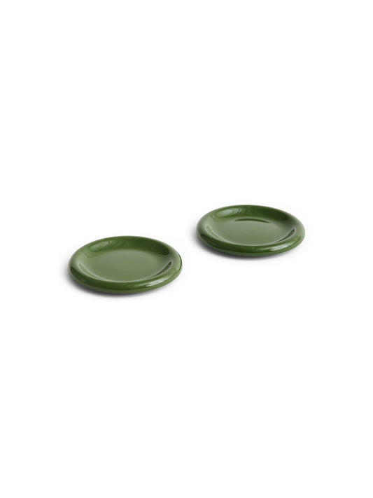 Side angle of two HAY Barro terracotta 18cm plates showcasing a fresh high-gloss green glaze and distinctive natural rolled edges.