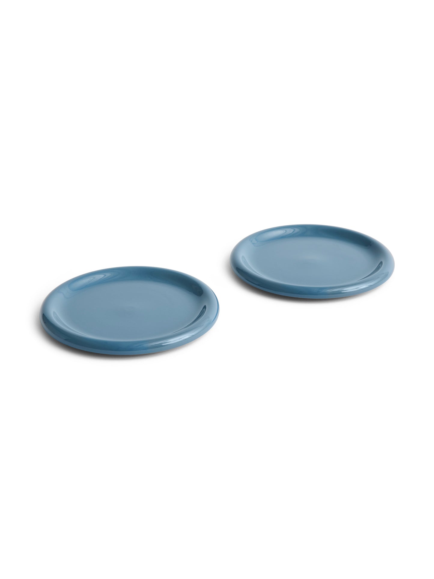 Side angle of two large 24cm HAY Barro terracotta dinner plates showcasing a rich high-gloss dark blue glaze and distinctive natural rolled edges.