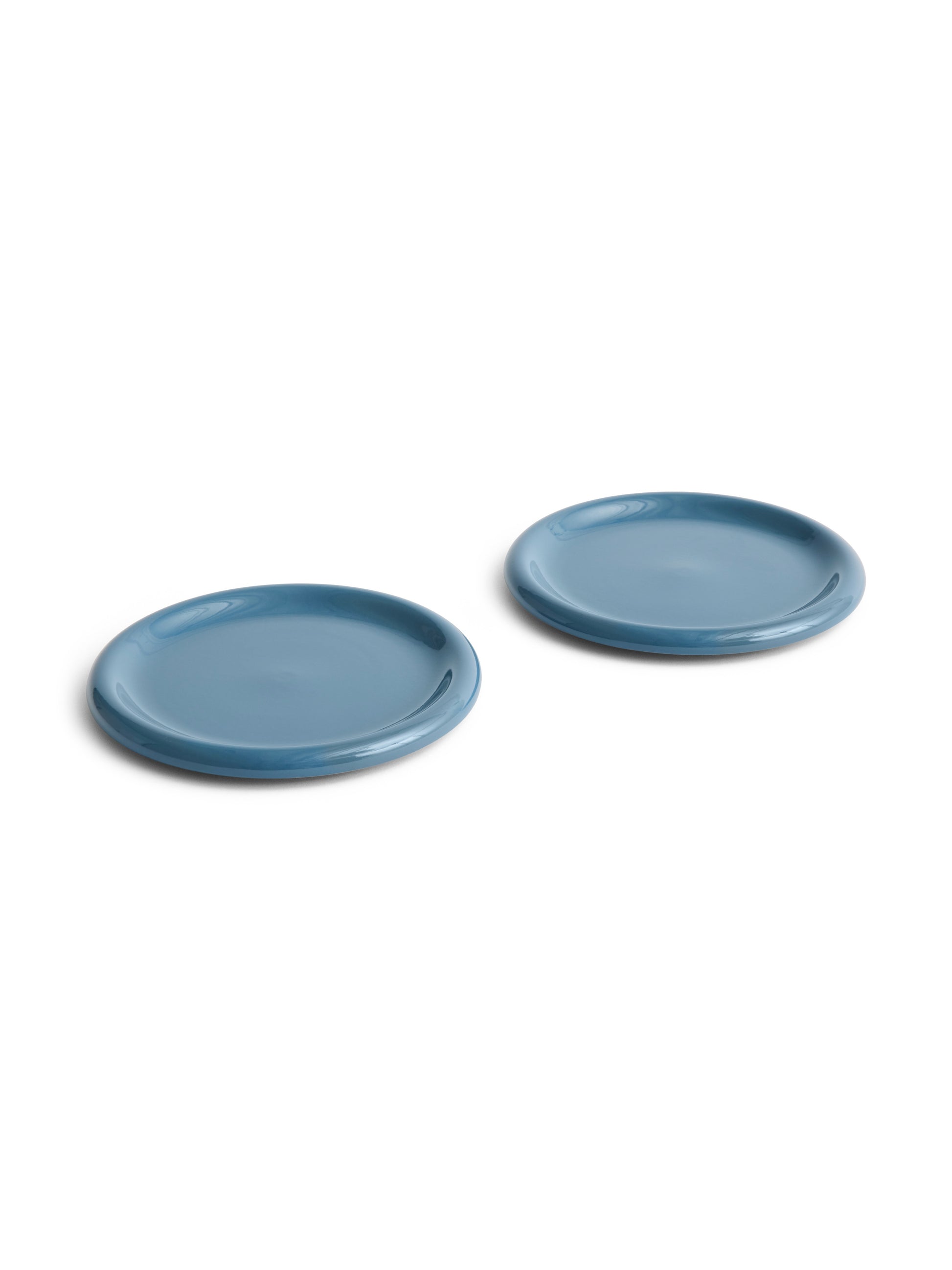 Side angle of two large 24cm HAY Barro terracotta dinner plates showcasing a rich high-gloss dark blue glaze and distinctive natural rolled edges.