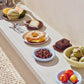 Close-up veiw of the outdoor setting of Hay light blue Barro bowls, paired with other Hay tableware products. 
