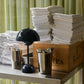 &Tradition Verner Panton Flowerpot VP9 Portable Table Lamp in Steel Blue on a stainless steel shelving next to napkins and cutlery.