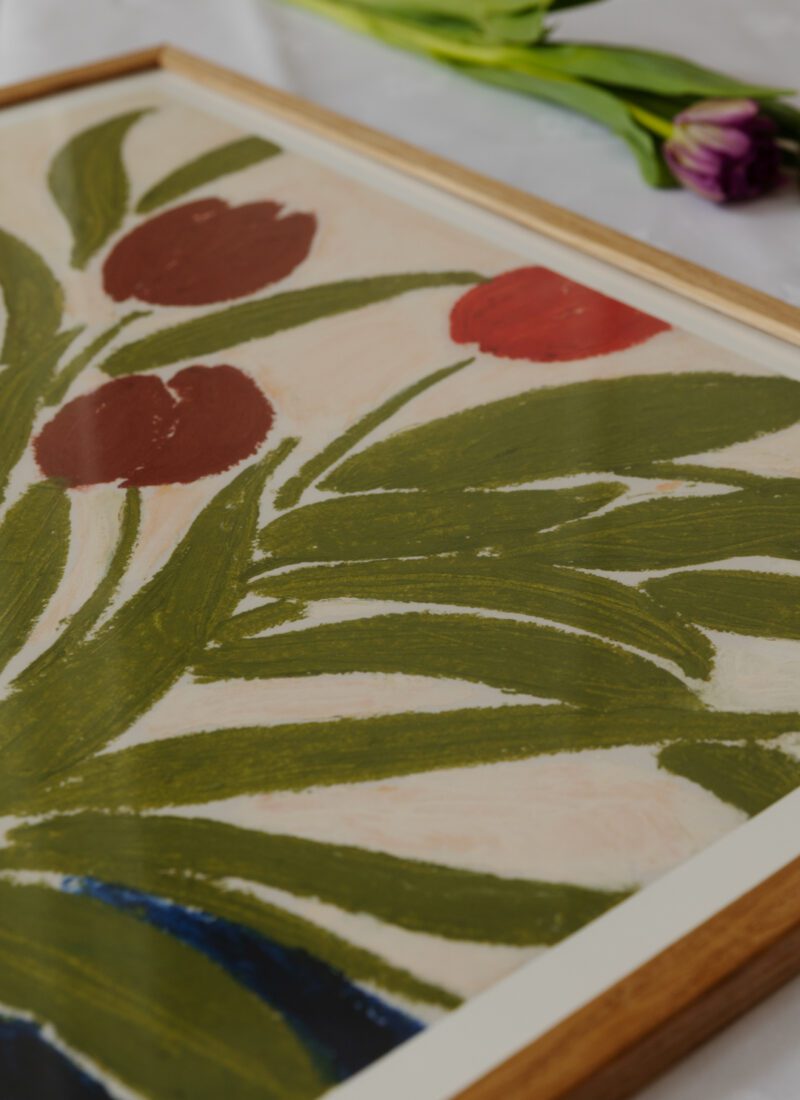 A closeup of the art print Tulips in a Blue Vase by Anine Cecilie Iversen in light wooden frame.