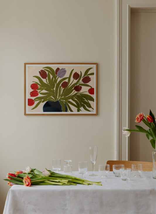 A lifestyle shot of Art print  Tulips in a Blue Vase by Anine Cecilie Iversen with a table setting of wine glasses and tulips.