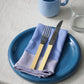 24cm HAY Barro terracotta dinner plate in dark blue on a table setting.