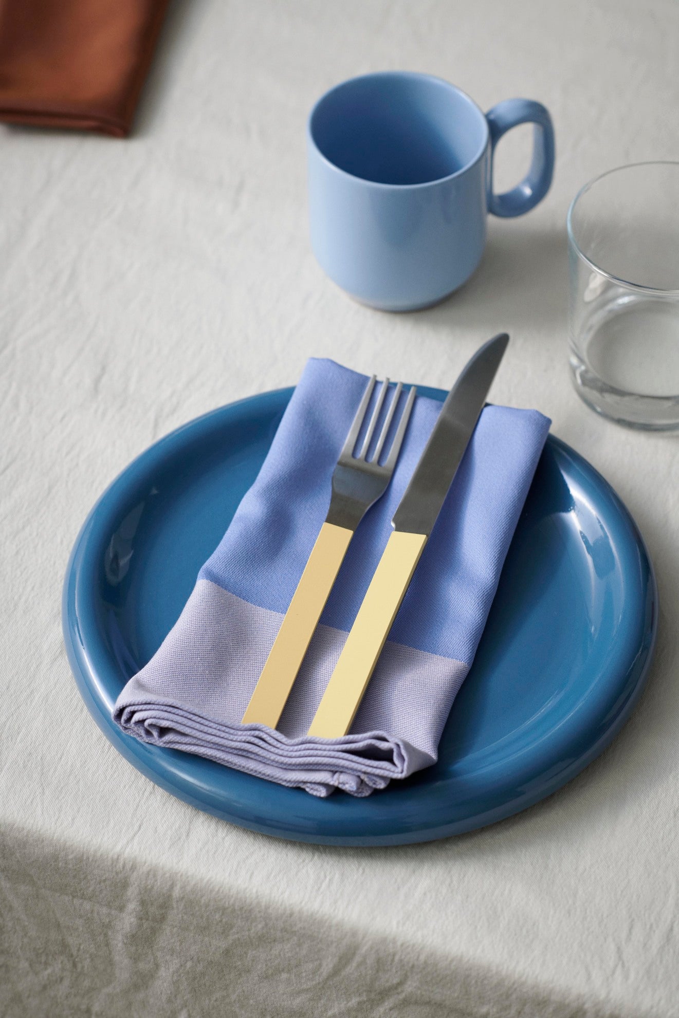 24cm HAY Barro terracotta dinner plate in dark blue on a table setting.
