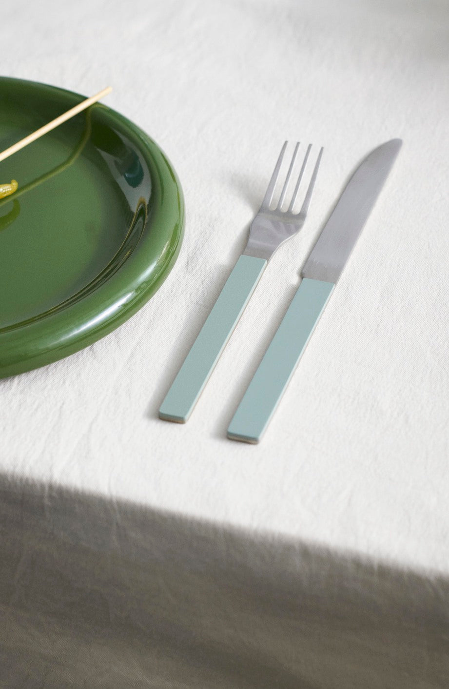 Hay Barro Plate 18cm in Green with a knife and fork on a white tablecloth