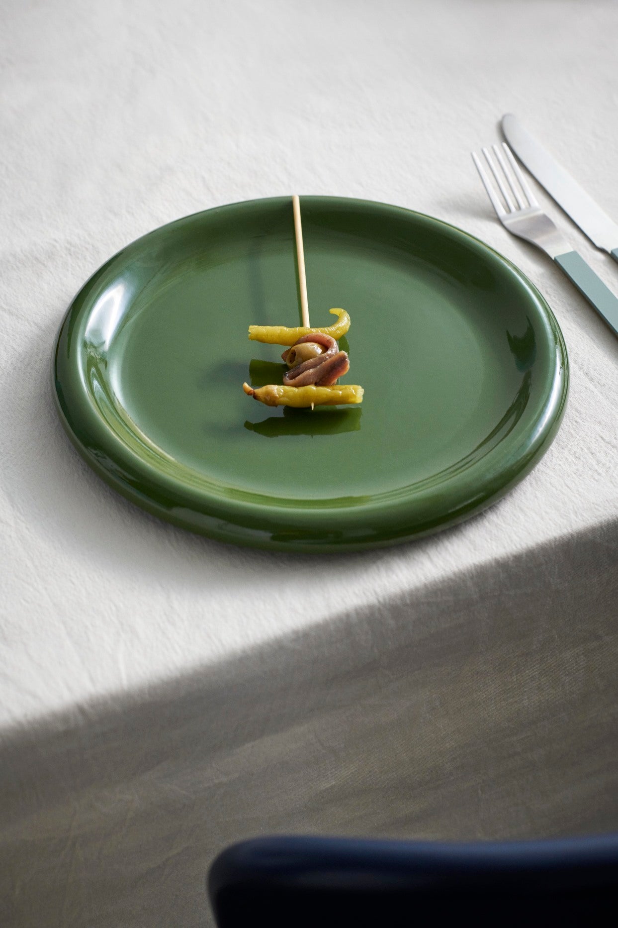 Hay Barro Plate 18cm in Green with skewered food on a white tablecloth