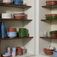 Corner of a homeware shop with wooden shelves displaying various Hay Barro plates.