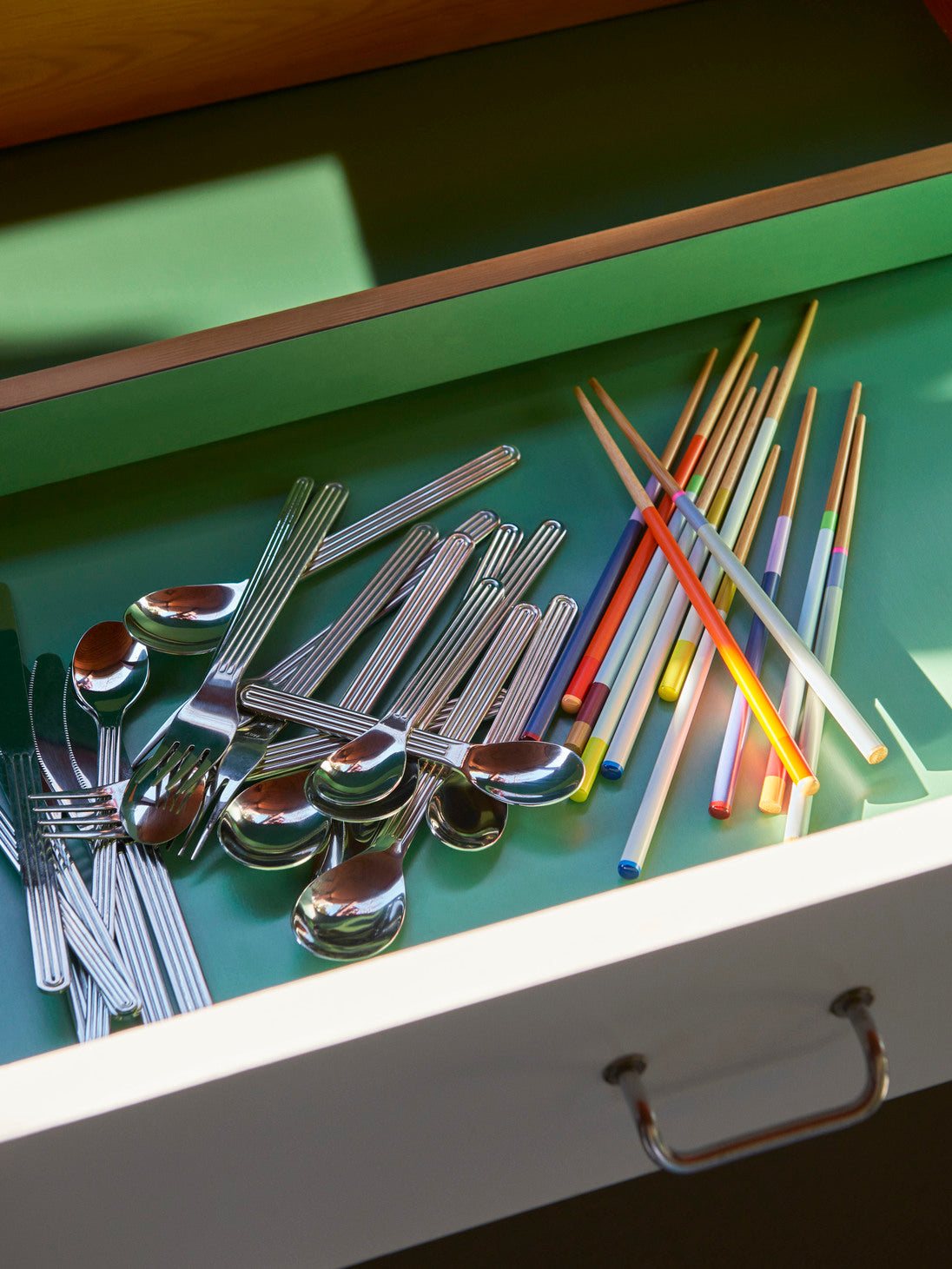 A lifestyle shot of four pairs of HAY Colour Sticks crafted from bamboo, together with Hay stainless steel cutlery.