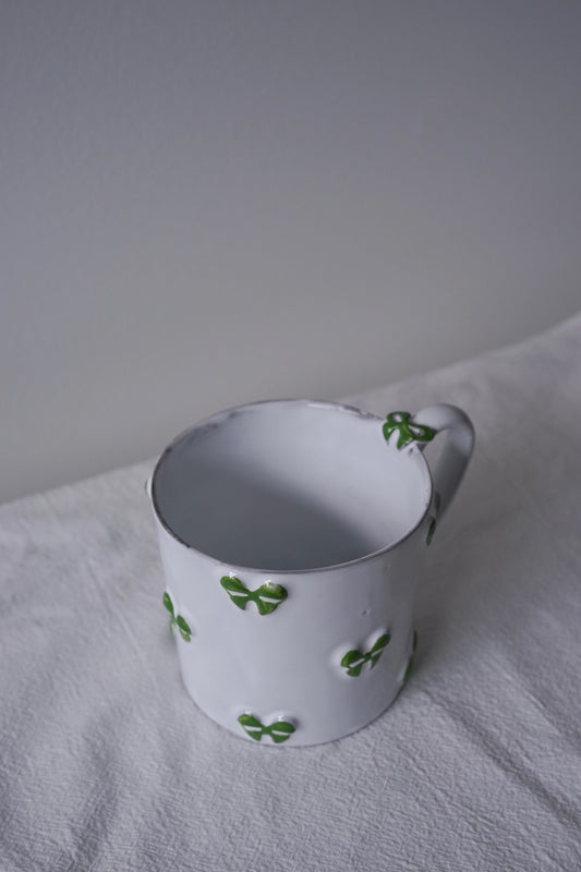 Close-up of CARRON Paris handmade white ceramic Nœud-Nœud Trianon mug featuring a hand-painted leaf green bow handle detail.