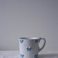 CARRON Paris handmade white ceramic Nœud-Nœud Trianon mug in medium, featuring a hand-painted sky blue bow detail.