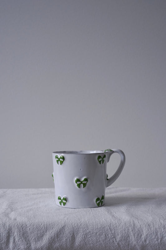 CARRON Paris handmade white ceramic Nœud-Nœud Trianon mug featuring a hand-painted leaf green bow handle detail
