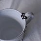 Close up of Carron Paris Noeud Noeud mug in black feauring hand-painted black bow handle detail.